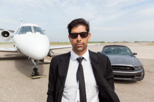 Portrait of confident male entrepreneur in front of car and private jet
